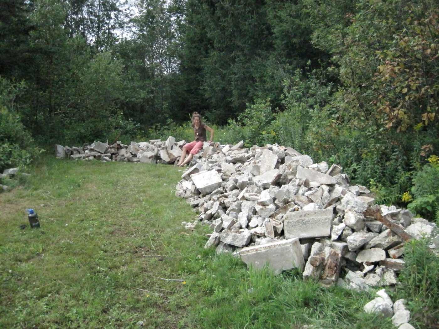 4 août 2010 : les débris sortis du bunker, empilés dans le champ. Amandine se repose de son travail herculéen.