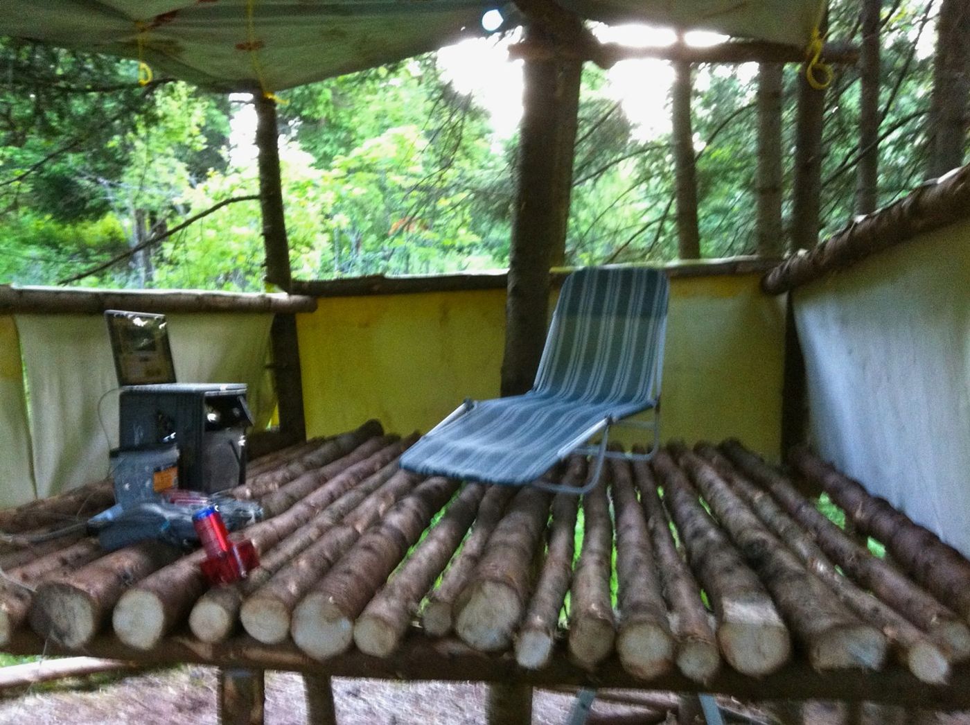 7 juin 2012 : le plancher de rondins d'une cabane, une chaise longue, des outils.