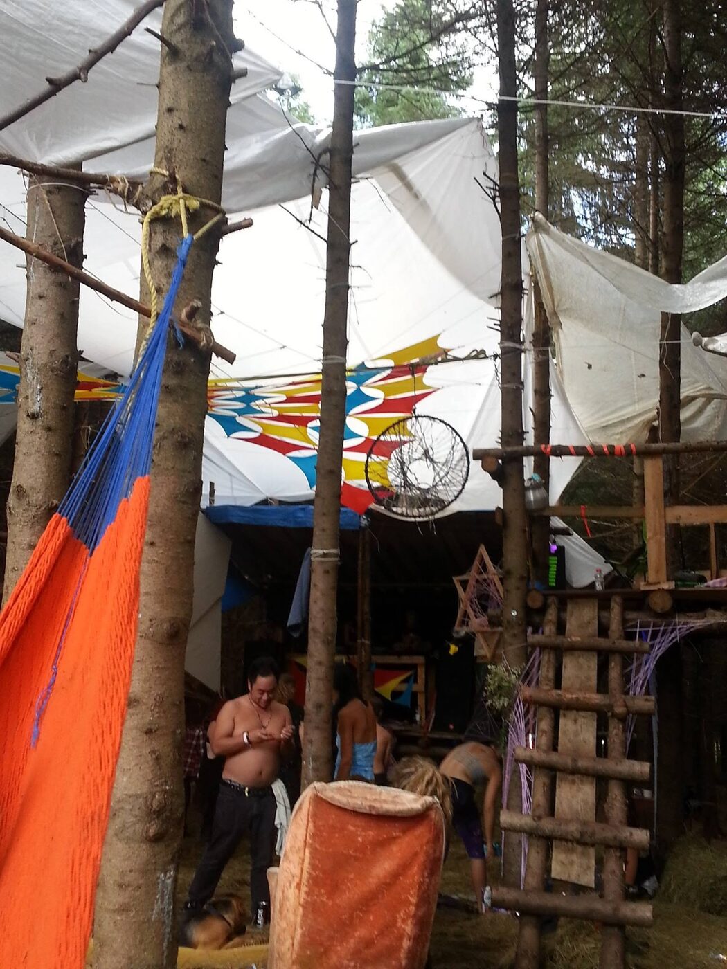 Hamac, bidons et cabane sur pilotis, à côté de la scène.