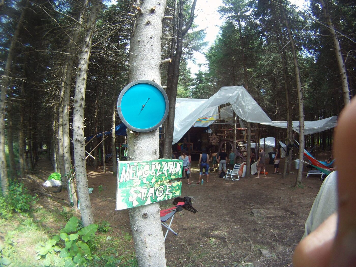 L'entrée du camp, un panneau cloué à un arbre, les tentes sous les toiles.